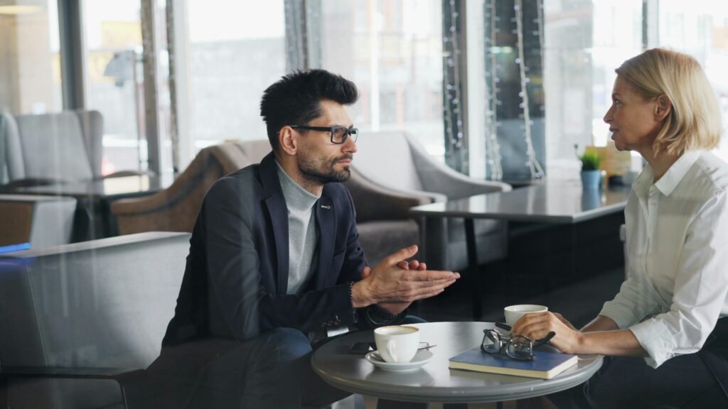 Man and woman in a quiet New York café engaged in a private, focused conversation during a codependency coaching consultation.