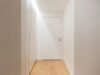 Closed door at the end of a quiet sunlit hallway, representing a young adult withdrawn during Failure to Launch